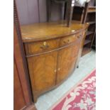 A mahogany bow fronted cabinet having three drawers above cupboard doors