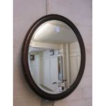 An early 20th century oak oval bevel glass mirror