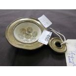 A Victorian/Edwardian enamel tea strainer in brass surround