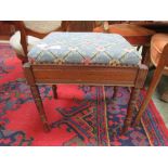 An early 20th century walnut music stool with needlework seat