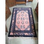 A Chinese rug, the border enclosing a salmon pink ground field for floor use