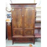 An early 20th century mahogany wardrobe, the cavetto cornice over two paneled cupboard doors and one