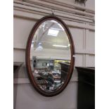 An early 20th century walnut framed oval bevel glass mirror