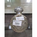 A cut glass perfume bottle with silver hallmarked top and collar