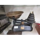 A set of black painted scales with weights and brass tray