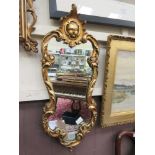 An ornate gilt framed mirror with masque design