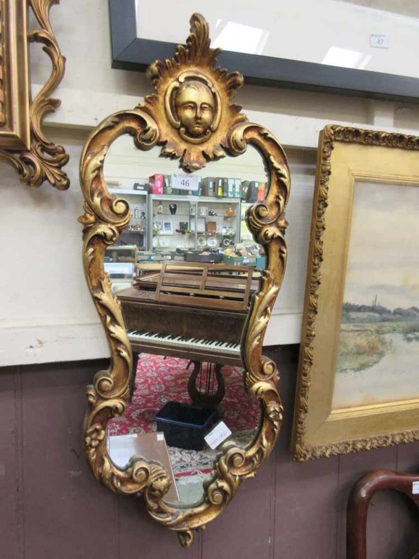 An ornate gilt framed mirror with masque design