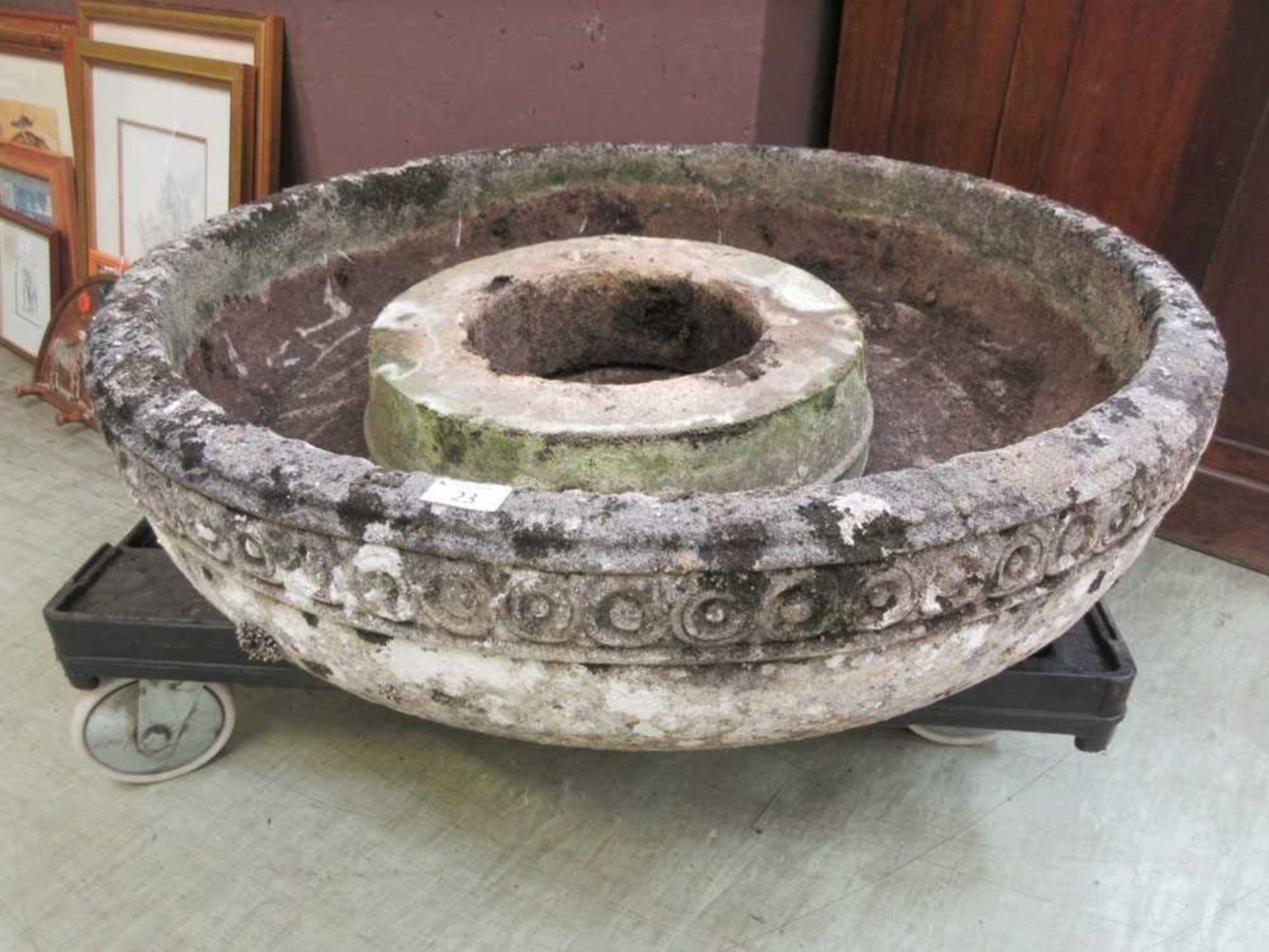 A large composite stone garden basin with decorative banding on sockel