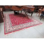 A large hand woven Persian rug, the multi-line enclosing a red ground field with arabesques (321cm