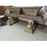 A composite stone garden bench, the moulded seat supported on recumbent lions