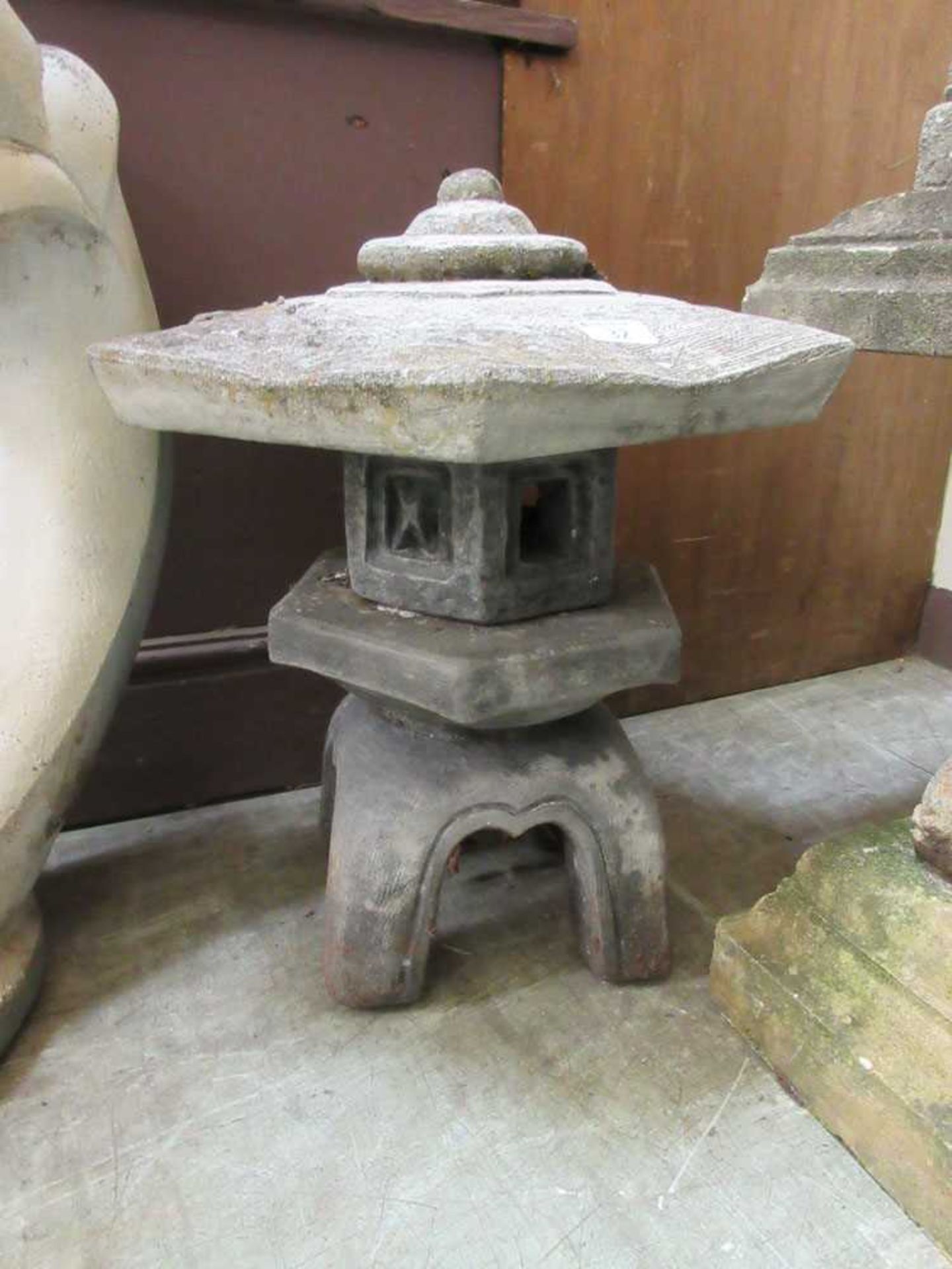 A composite stone Japanese style garden lantern on scroll support