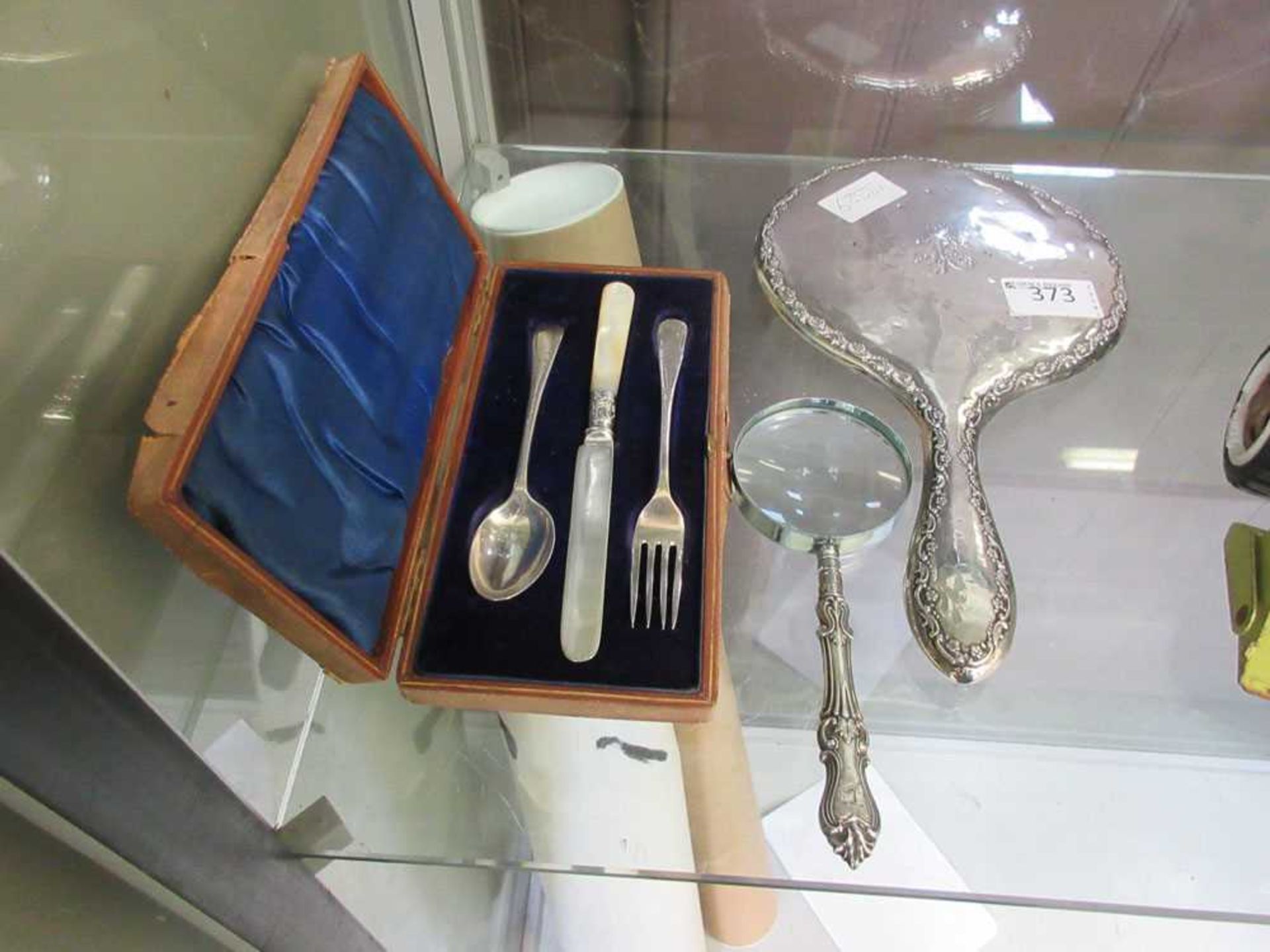 A silver hallmarked backed mirror, a silver hallmarked handled magnifying glass and a cased set of