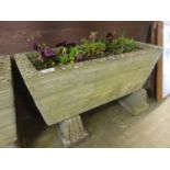 A rectangular weathered stoneware planter on blocks with flowers