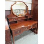 An Edwardian Sheraton revival serpentine fronted dressing table having swing mirror with trinket