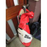 A red and white Wilson golf bag together with a selection of golf clubs