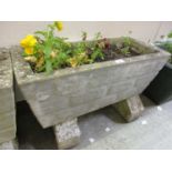 A weathered rectangular stoneware planter with blocks and flowers