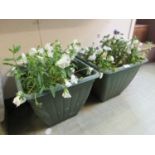 A pair of green PVC green planters with plants