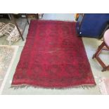 A handwoven Afghan rug, the triple line border surrounding the red ground field with octagons, 175