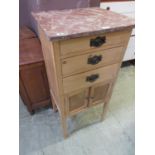 An early 20th century pine cabinet having three drawers above a pair of cupboard doors with a pink