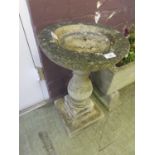 A weathered stoneware bird bath