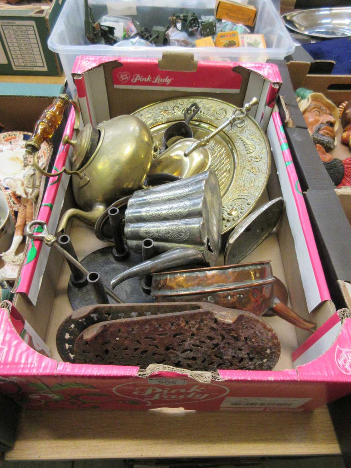 A tray containing a quantity of metalware to include cast iron trivets, copper kettle, brass