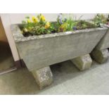 A weathered rectangular stoneware planter with blocks and flowers