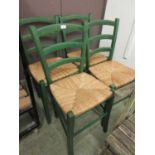 A set of four green painted wooden chairs with seagrass seats