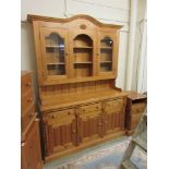 A modern pine dresser, the plate rack with glazed doors over the base with three drawers and paneled