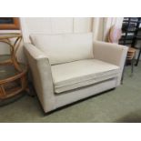 A modern two seat settee in beige fabric