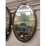 A mahogany and line inlaid oval bevel glass mirror