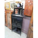 An Edwardian ebonised corner display cabinet, the bevelled mirrored back panel over bevel glazed