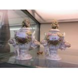 A pair of Dresden ceramic lidded pots with putto designChip to top of one lid. One putto's wing