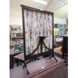 An early 20th century mahogany fire screen with pleated floral panel and candle shelf