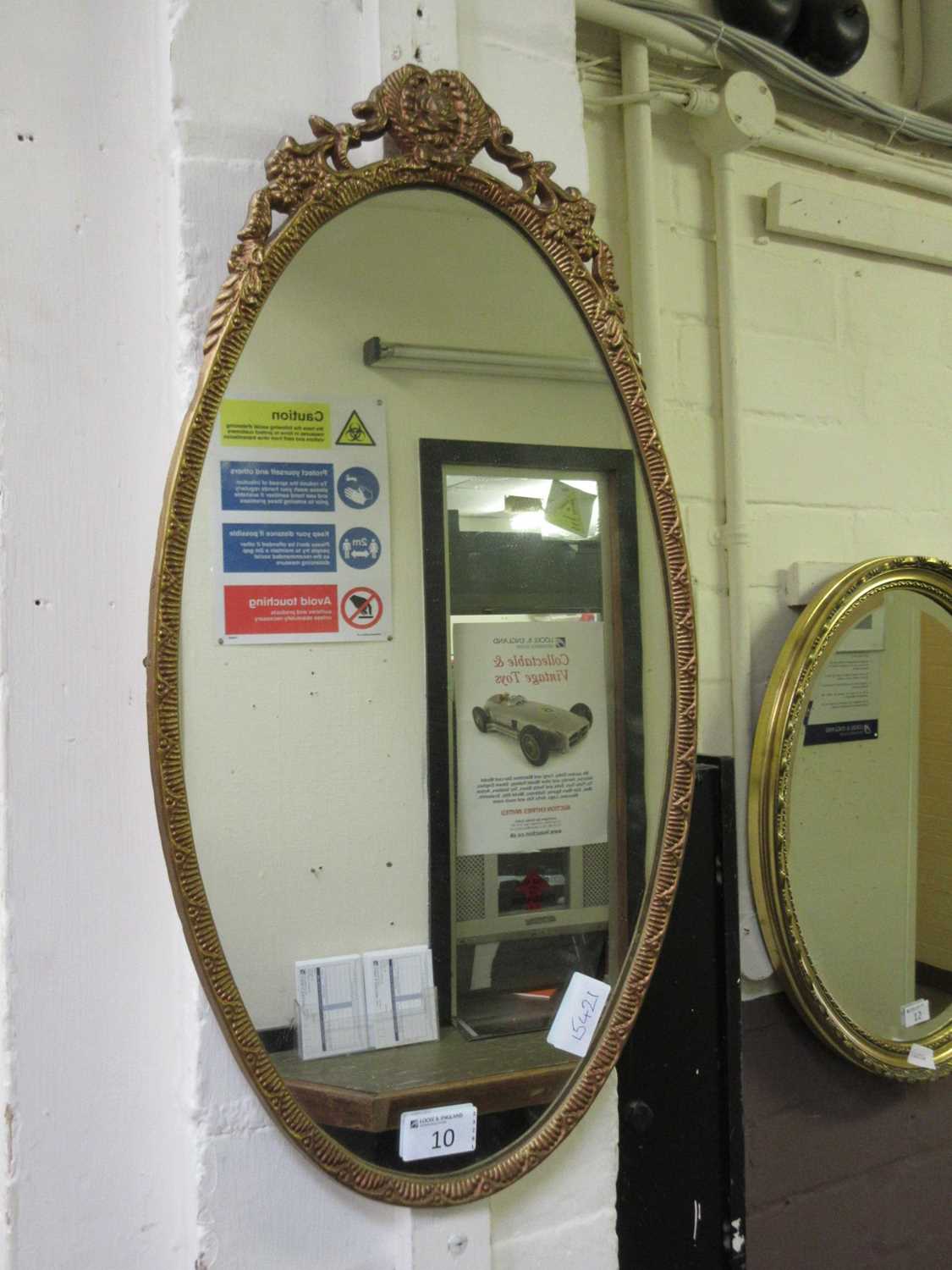 An ornate gilt metal oval mirror