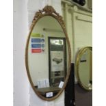 An ornate gilt metal oval mirror