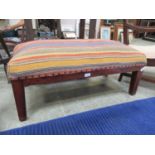 A modern footstool with striped woven upholstered top