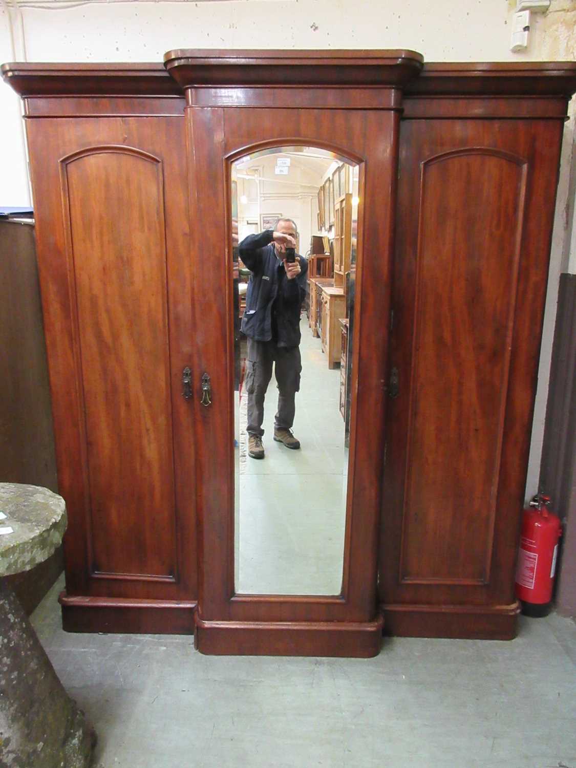 A Victorian mahogany three door wardrobe, with beveled mirrored centre door flanked by two other