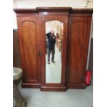 A Victorian mahogany three door wardrobe, with beveled mirrored centre door flanked by two other