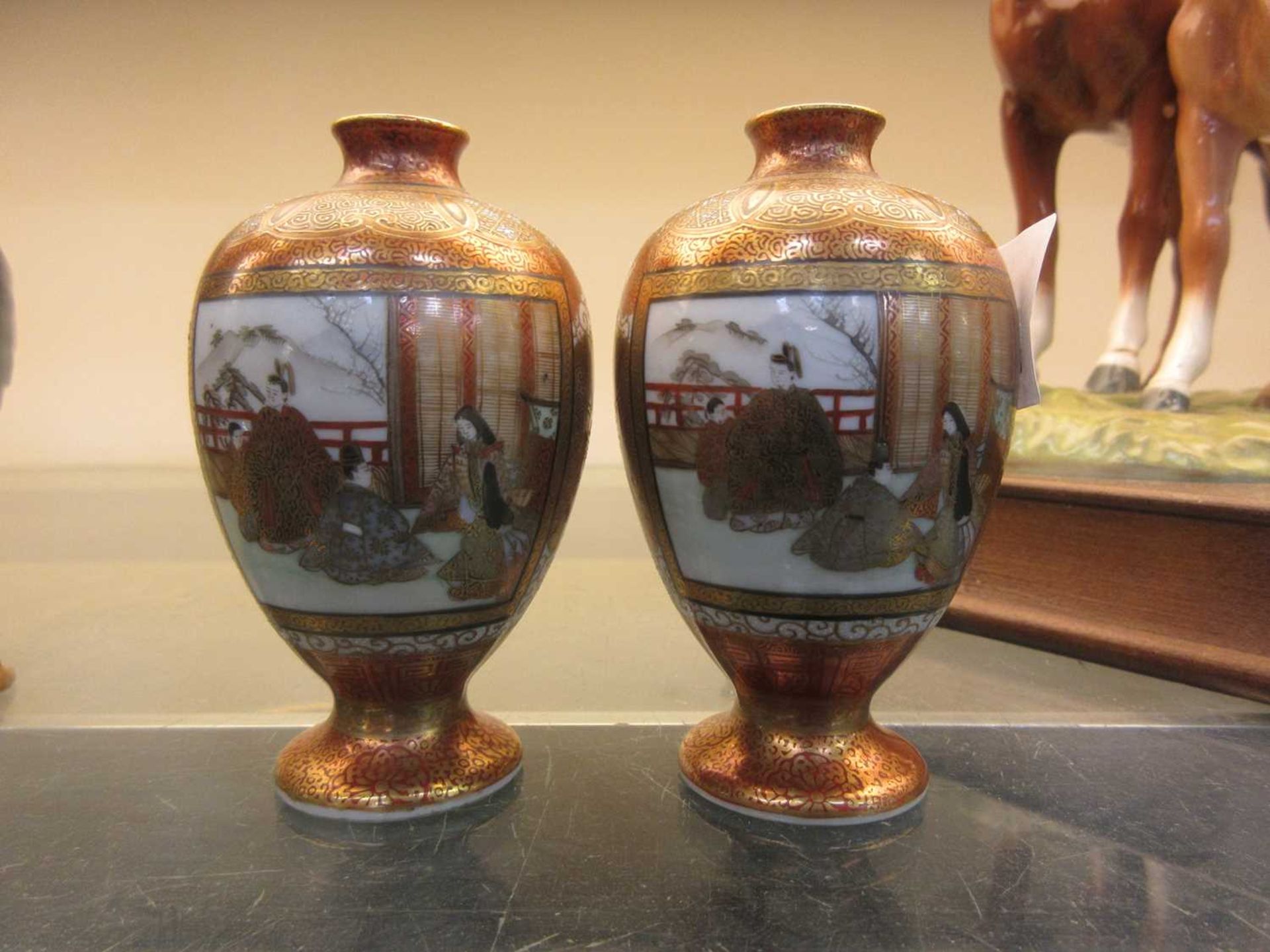 A pair of miniature Satsuma ware bud vases depicting interior scenes