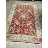 A hand woven Persian rug, the border with animals motifs surrounding a red ground field with