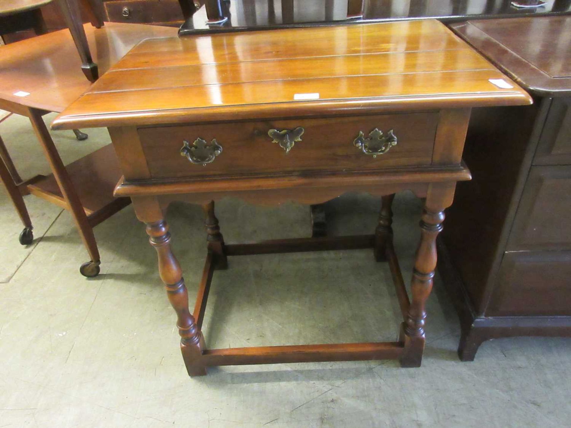 A reproduction cherrywood single drawer side table on turned legs