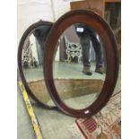 An early 20th century mahogany framed oval bevel glass mirror along with one other