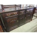 A reproduction oak 18th century style sideboard, the top over three drawers and two arch top field
