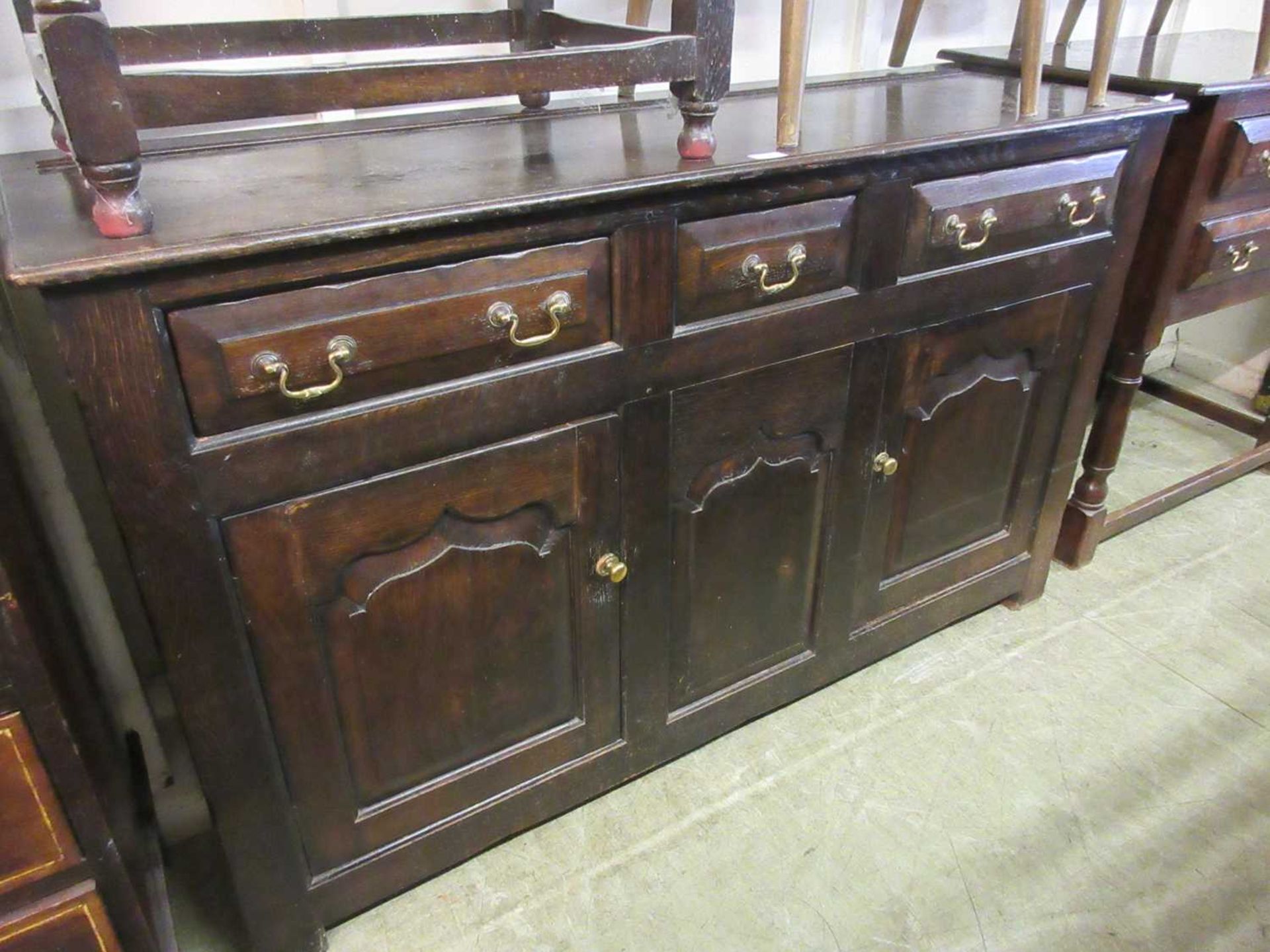 A reproduction oak 18th century style sideboard, the top over three drawers and two arch top field