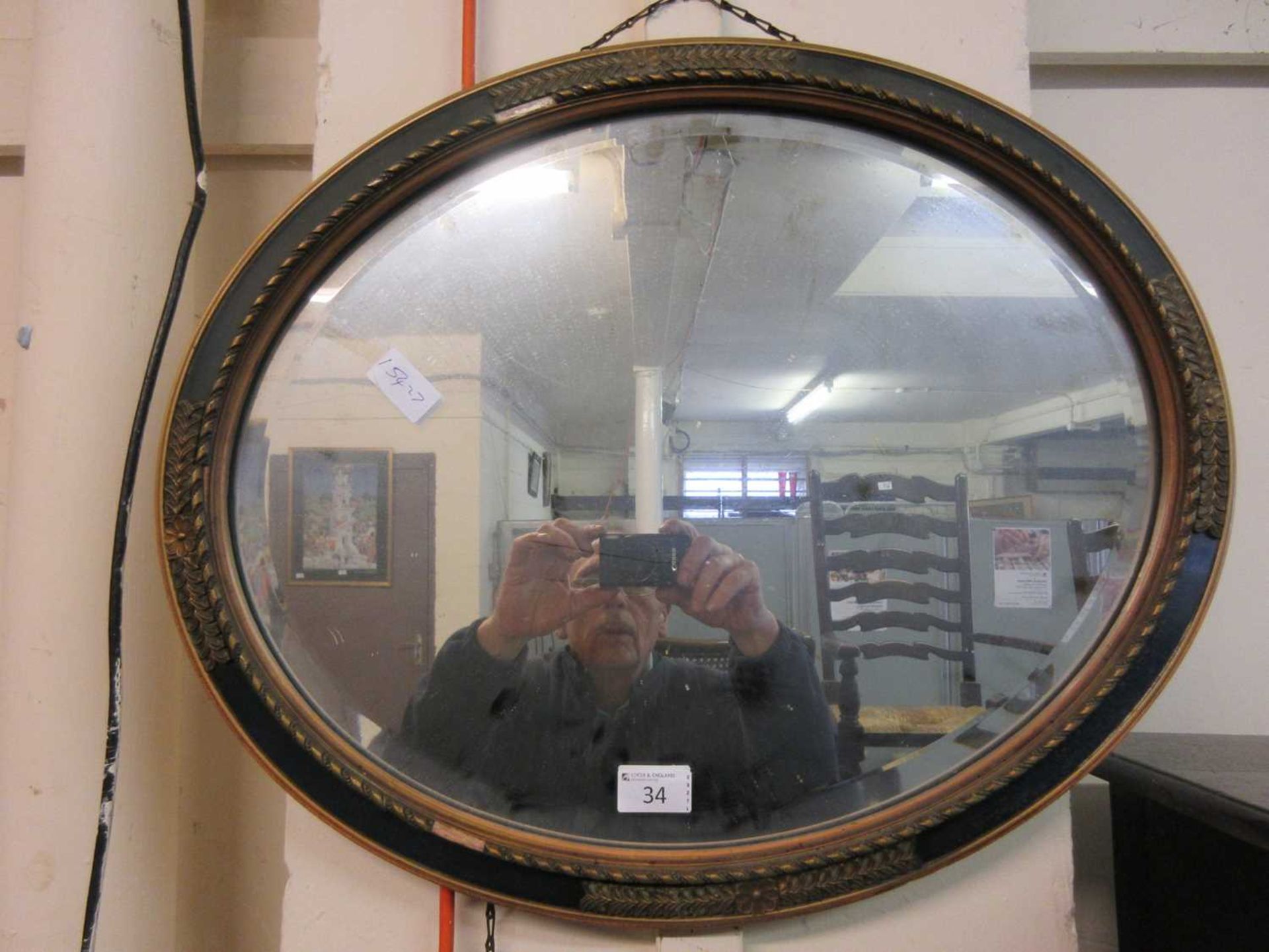 An early 20th century parcel gilt oval bevel glass mirror