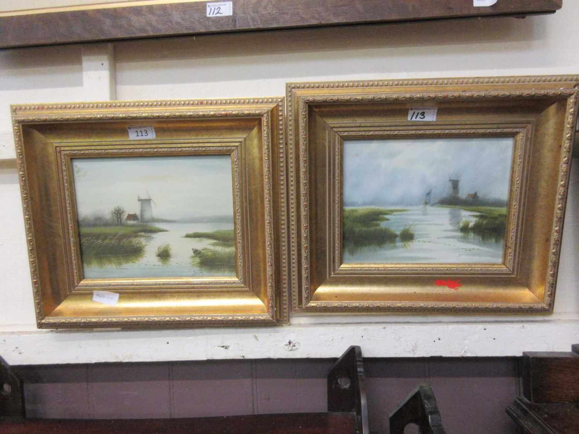 A pair of gilt framed artworks of windmills signed James