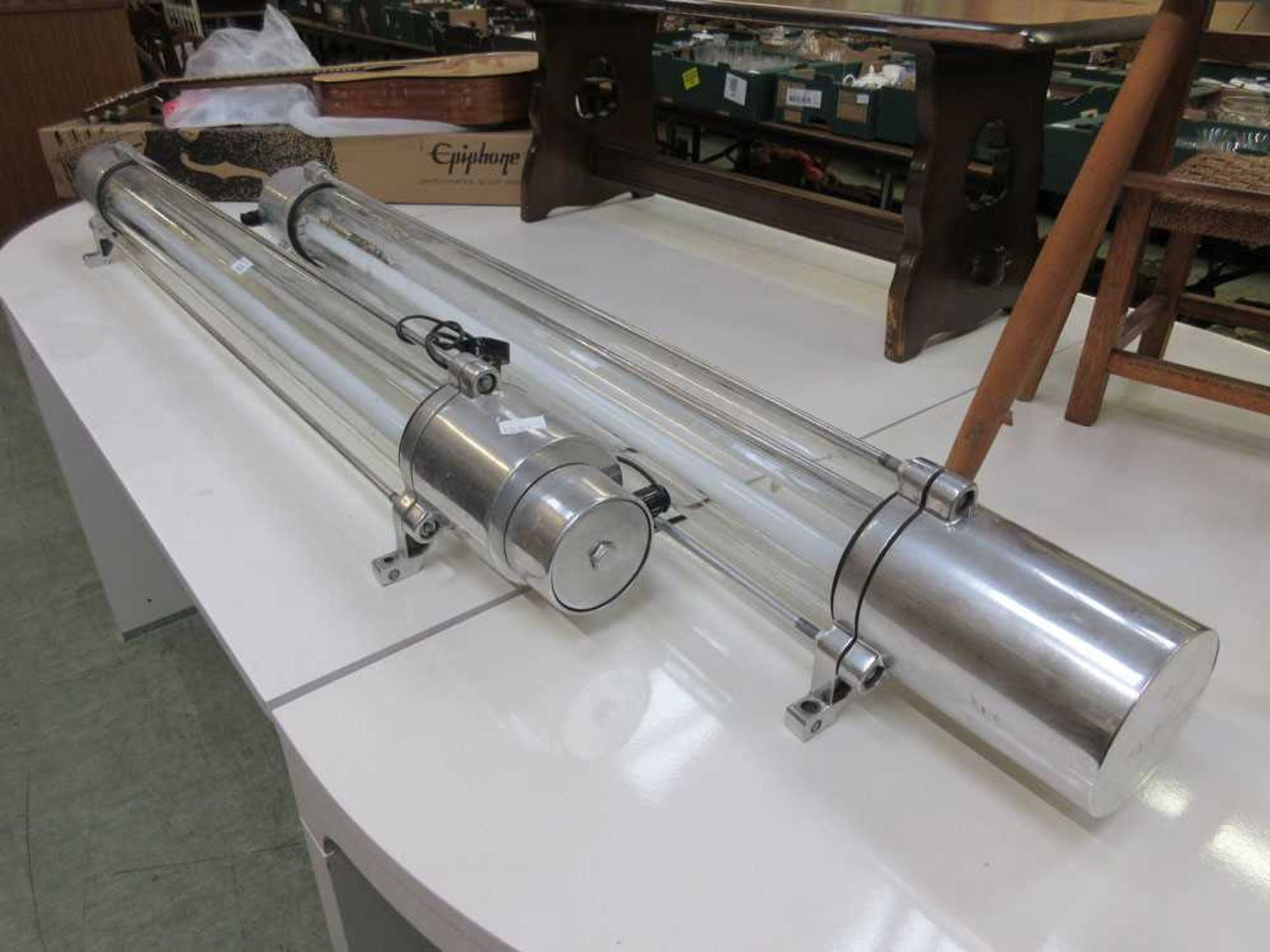 A pair of 20th century fluorescent light fittings with chrome ends flanking the glass tube