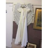 An ivory wedding dress along with a pair of metalwork angel wings