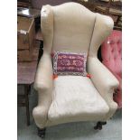 An early 20th century wingback armchair on squat cabriole legs