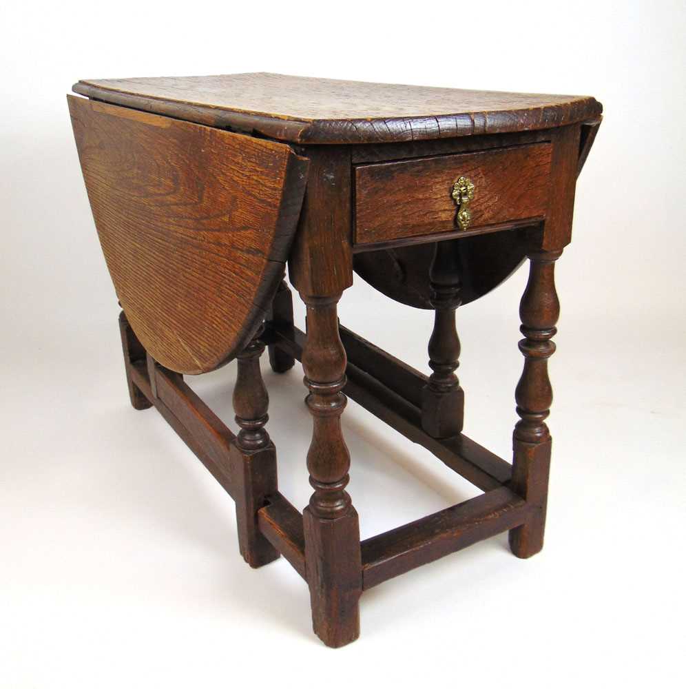 An early 18th century oak drop leaf table, the oval top supported on a single gate action over a - Image 2 of 2